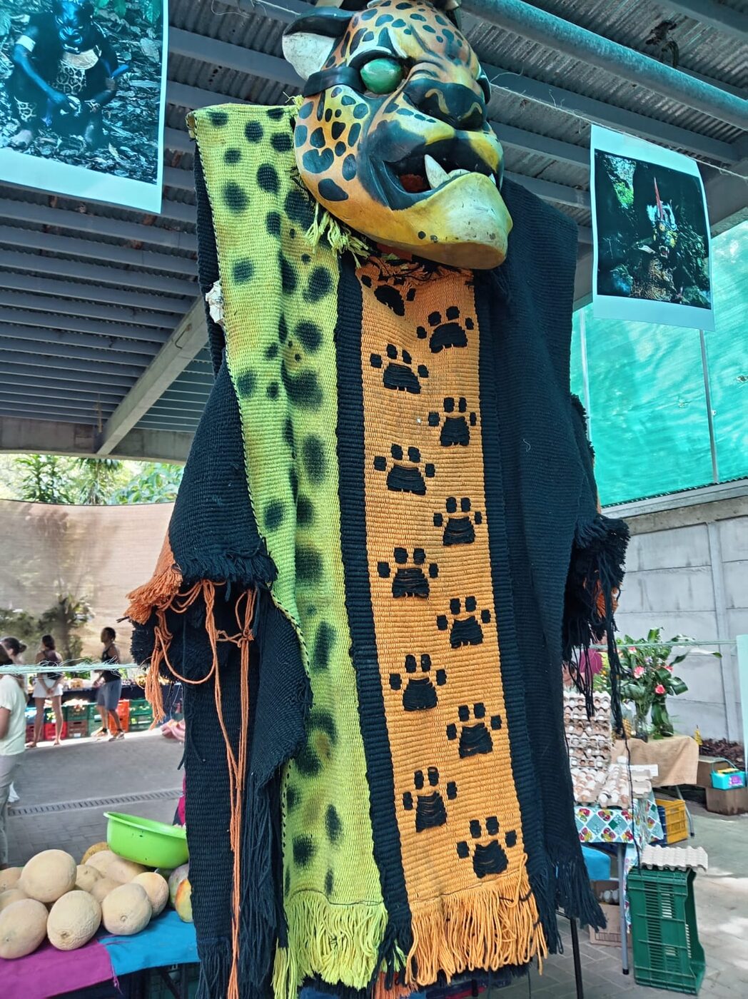 Hand-woven Boruca textile with a jaguar-paw motif, displayed beside a carved jaguar mask